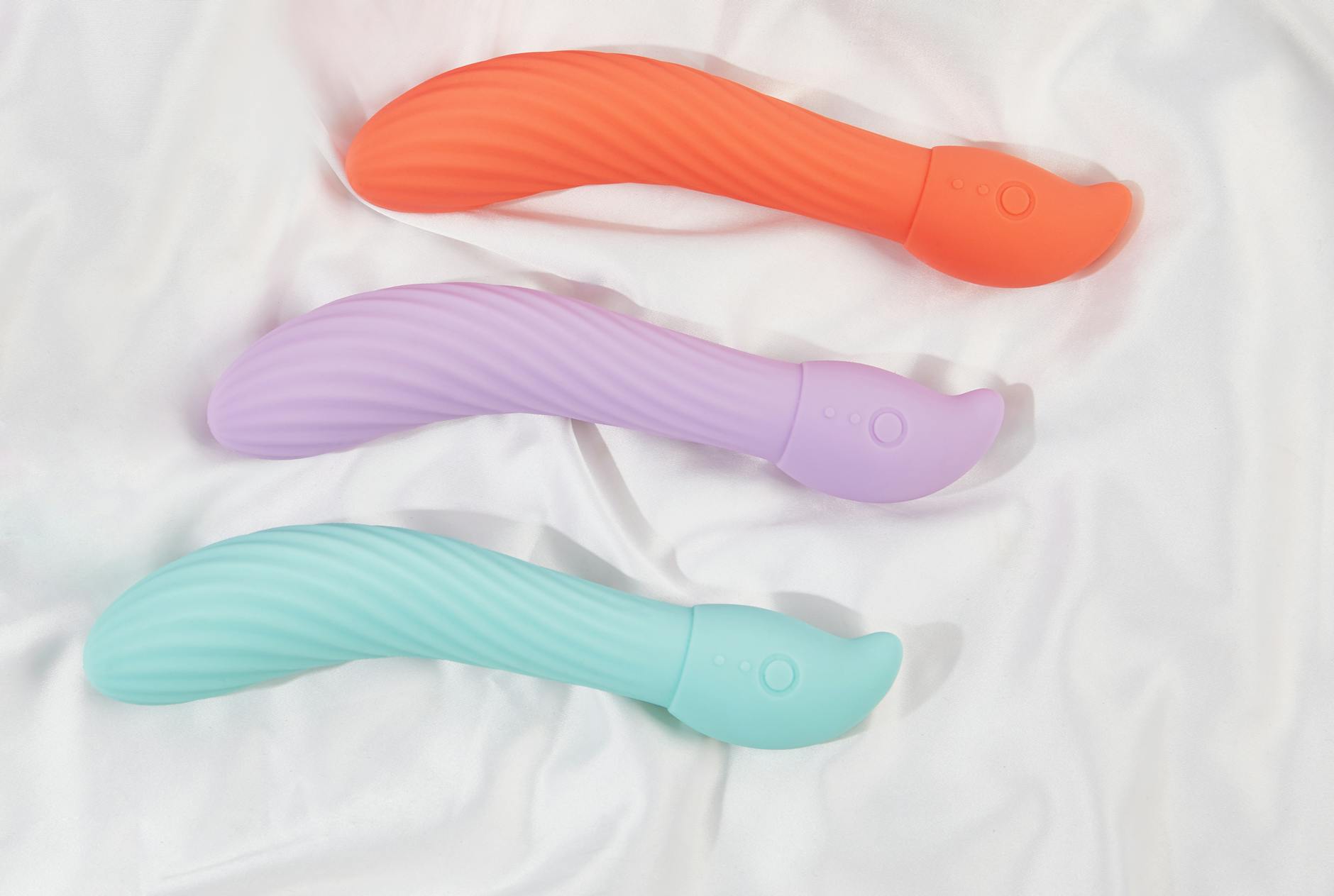 A stylish teal vibrator on smooth white silk fabric, representing discreet adult wellness.