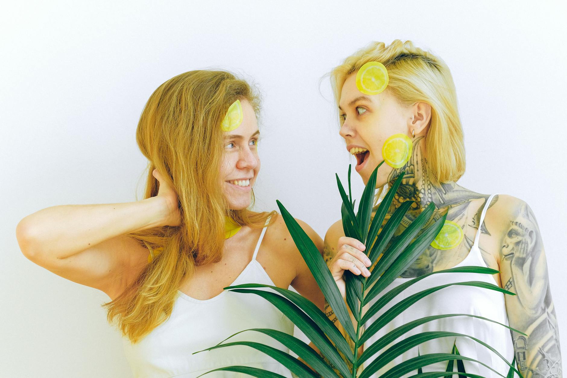 Two women smiling and laughing together with lemon slices, expressing joy and vitality
