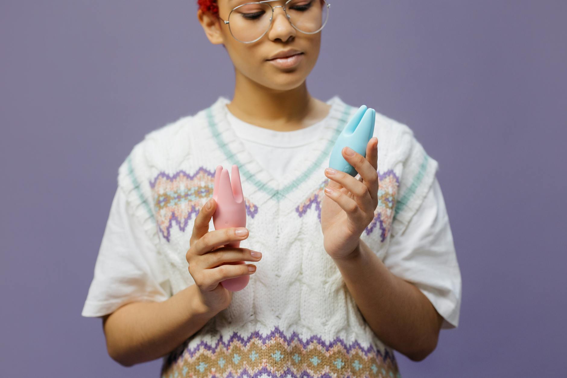 Woman holding colorful vibrators in contemplative pose, representing exploration during hormonal changes