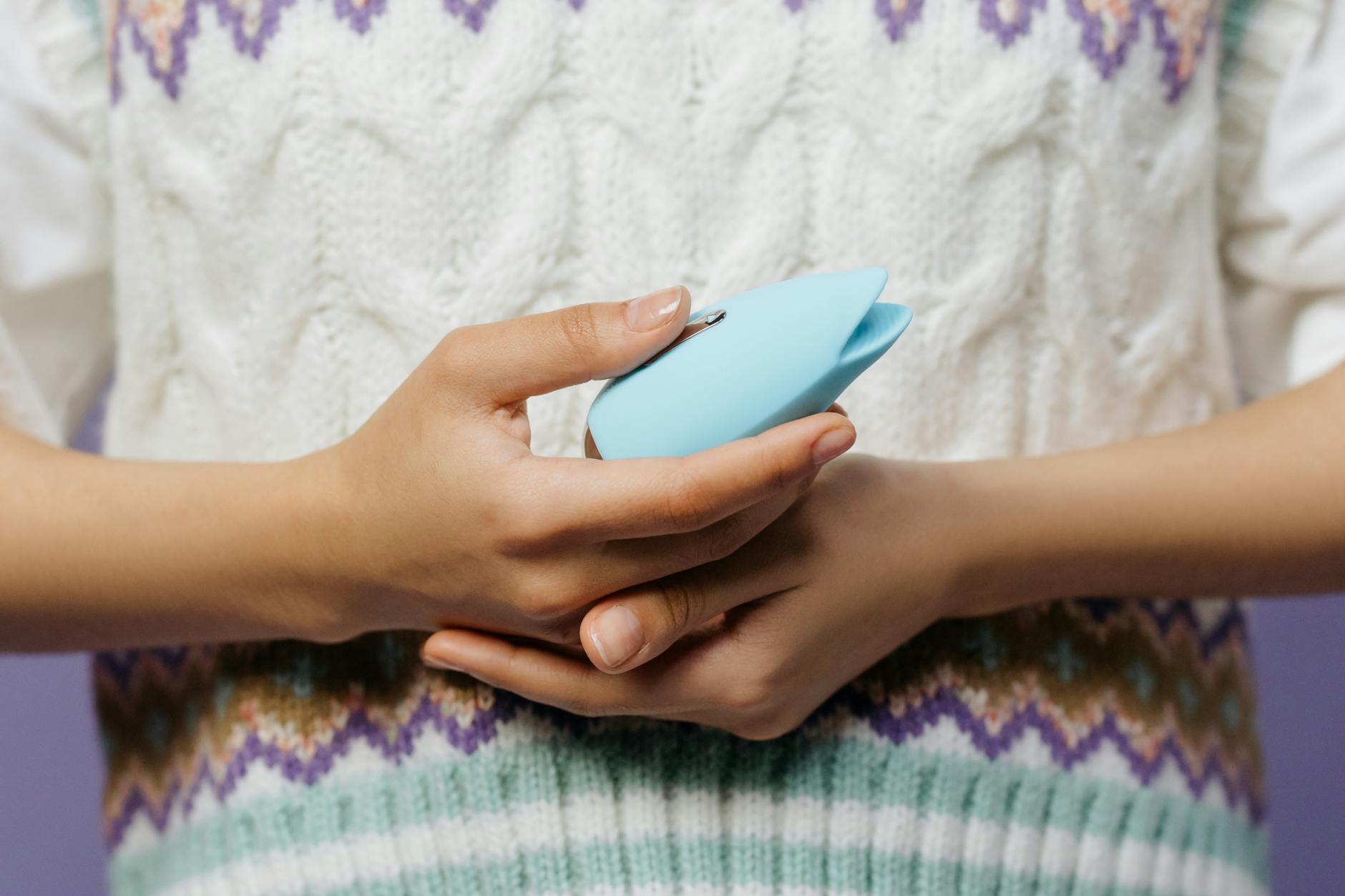 Woman holding blue and pink silicone vibrators while considering how to approach partner conversation