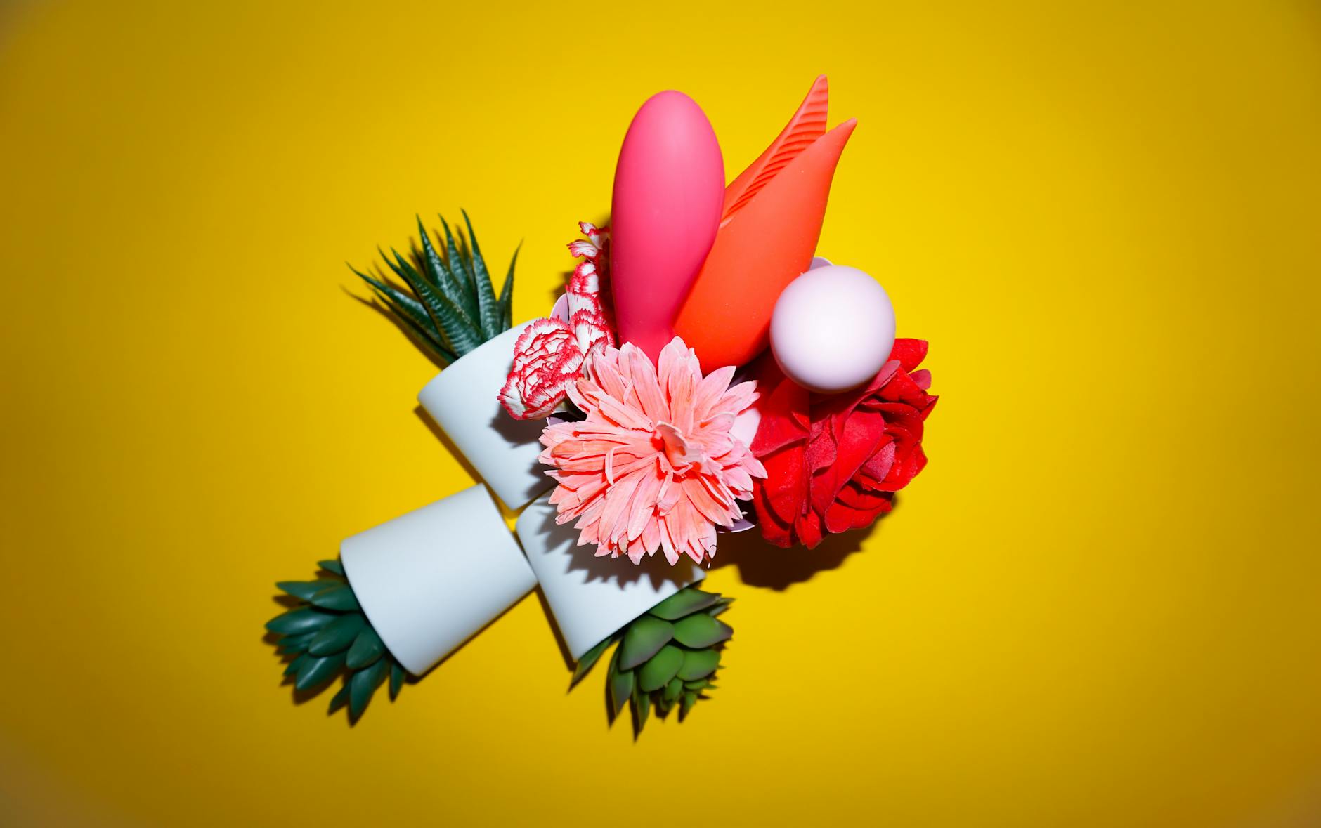 Yellow silicone vibrator surrounded by fresh bananas on a yellow background.
