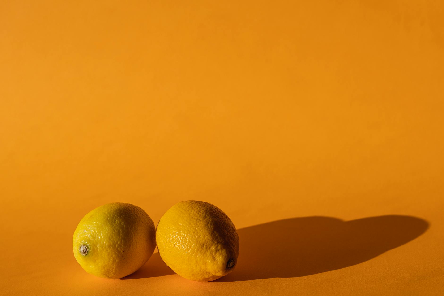 A close-up of a hand holding an orange vibrator against a minimalistic purple backdrop, showcasing modern sensuality and tactile connection.